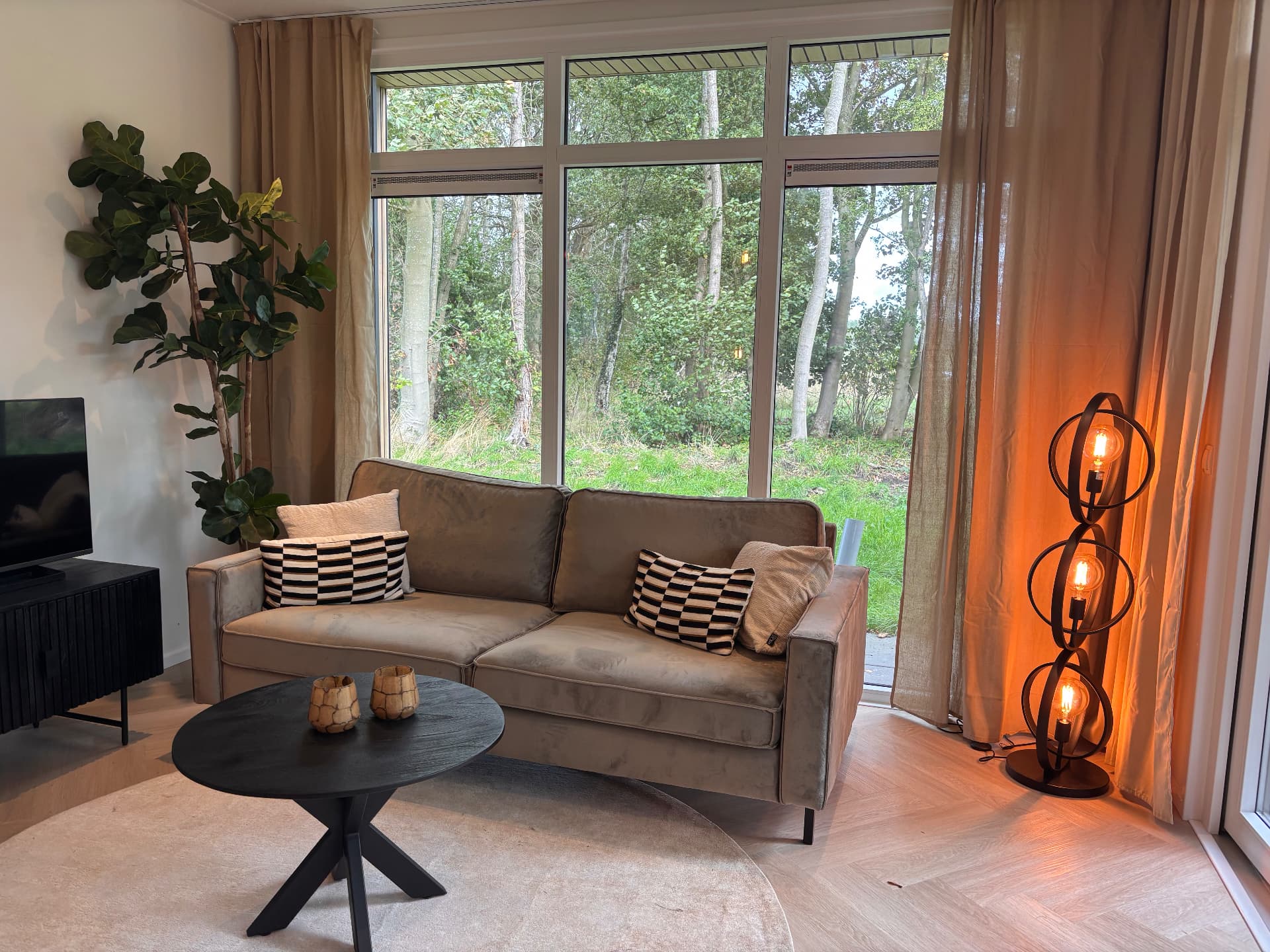 Lichte woonkamer met hout, grote ramen en zithoek